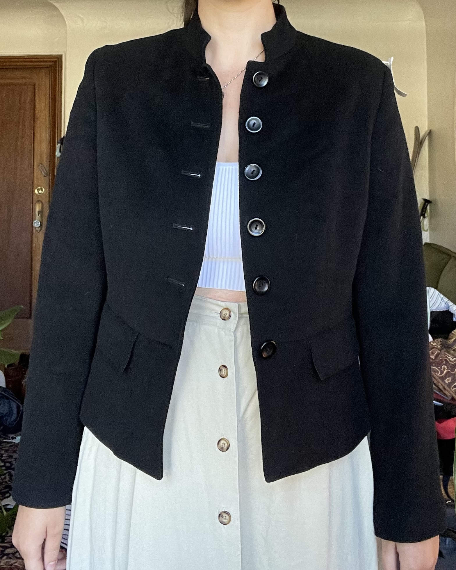 girl wearing a plain black jacket with buttons up the front, shown from the front